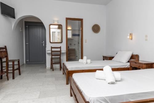 a room with three beds and a table and chairs at Helios Beach Studios in Plaka