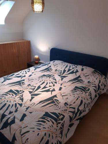 Bett in einem Schlafzimmer mit einer blauen und weißen Bettdecke in der Unterkunft Maison de paludier in Guérande