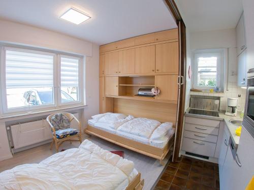 a bedroom with two beds and a desk and a kitchen at Ferienwohnung Emilia, FeWo Vermittlung Nordsee in Dangast