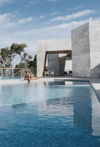two people sitting on the edge of a swimming pool at D-Resort Šibenik in Šibenik