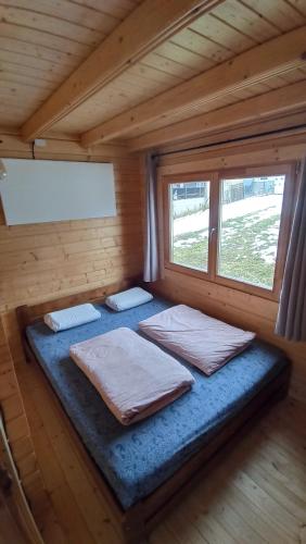 a bed in a wooden room with two pillows at Happy Cottage 