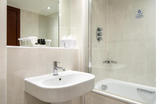 a white bathroom with a sink and a shower at Danubius Hotel Regents Park in London