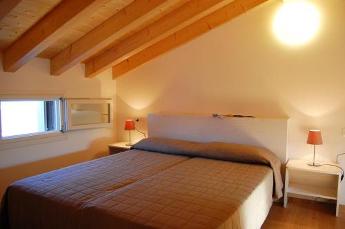 a bedroom with a bed and two lamps on two tables at Warm apartment with swimming pool in a village in Bibione