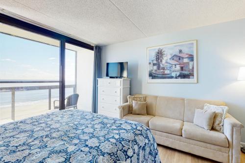 een slaapkamer met een bed, een bank en een raam bij Golden Sands 809 in Ocean City