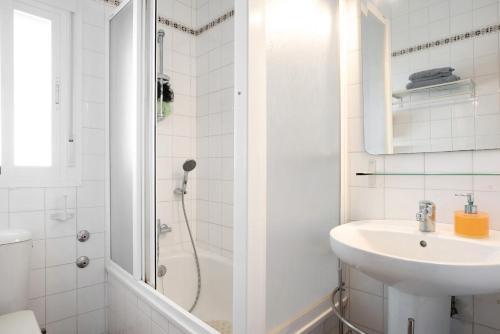 uma casa de banho branca com um chuveiro e um lavatório. em Las torres em Chiclana de la Frontera
