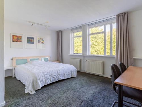 a bedroom with a bed and a desk and windows at Cosy apartment in Alkmaar with balcony in Alkmaar