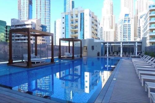 a swimming pool with chairs and buildings in the background at GuestReady - Stunning Marina Apt close to the beach in Dubai