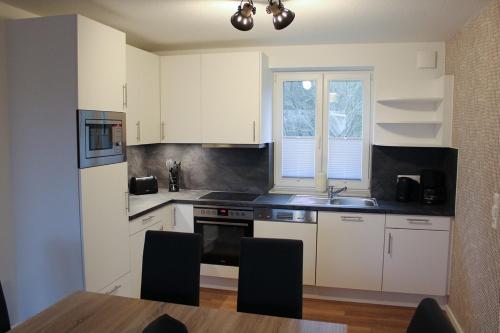 a kitchen with white cabinets and a sink and a table at LA2 f - Ferienreihenhaus LA2 in Schottwarden