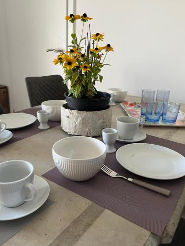 a table with white plates and cups and a plant at Ferienwohnungen Fritze Bürger in Schiefling am See