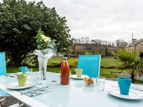 a white table with a vase of flowers and drinks at Holiday Home Le Clos Renard by Interhome in Commes