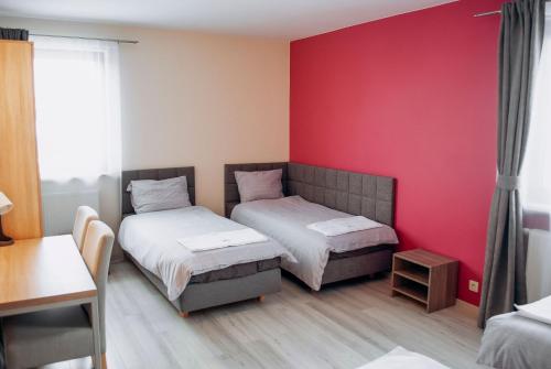 two beds in a room with a red wall at Redwood Hostel in Lublin