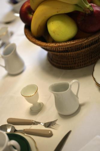 a table with a basket of fruit and utensils at Historical Suites VVM in Lecce