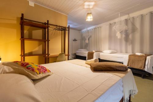 um quarto com 2 camas com lençóis brancos e um quarto em Pousada Recanto da Mata em Arraial d'Ajuda