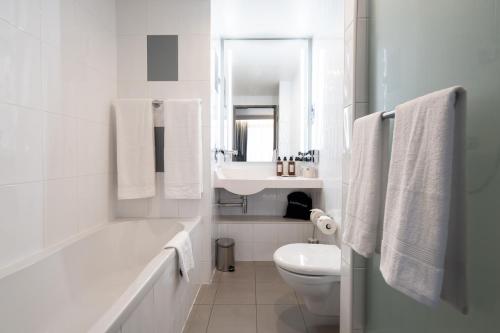 a white bathroom with a sink and a toilet at Novotel Vilnius Centre in Vilnius