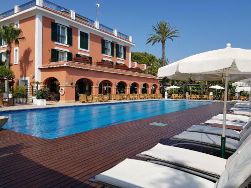 a swimming pool with lounge chairs and a building at Hotel MR Les Rotes in Denia