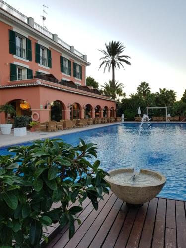 a swimming pool with a fountain in front of a building at Hotel MR Les Rotes in Denia