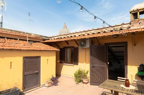 een geel huis met een patio ervoor bij La mansarda del Papa - Zen Real Estate in Rome