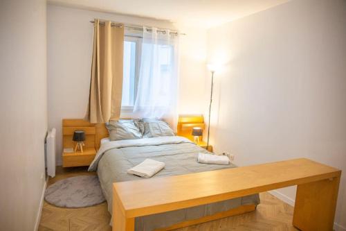 a bedroom with a bed with a wooden table at Grand 2 pièces balcon Parking porte PARIS in Aubervilliers