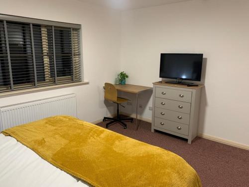 a bedroom with a bed and a tv and a desk at Premium Inn Apartments in Methley