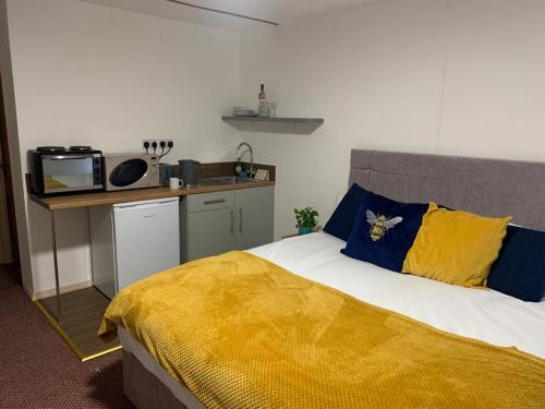 a bedroom with a bed with a yellow blanket and a kitchen at Premium Inn Apartments in Methley