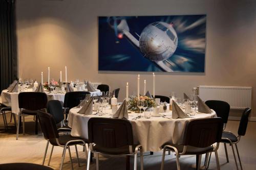 a conference room with tables and chairs and a painting at Park Inn by Radisson Oslo Airport Hotel West in Gardermoen