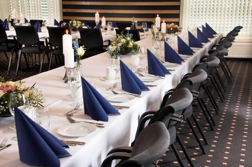 a long table with blue napkins and chairs in a room at Park Inn by Radisson Oslo Airport Hotel West in Gardermoen
