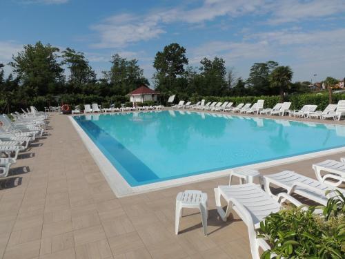 a large swimming pool with white chairs and chairs at Country House Country Club in Noghera