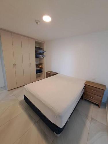 a white bedroom with a bed and a wooden cabinet at Dpto entero Condominio Altamira in Colonia Mariano Roque Alonso