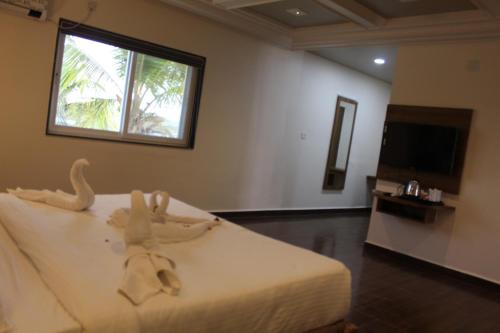 a bedroom with a bed with a window and a television at Flamingo Club and Resort Una 3 Km Away from Diu Check Post in Diu