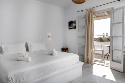 a white bedroom with a bed and a view of the ocean at Helios Beach Studios in Plaka