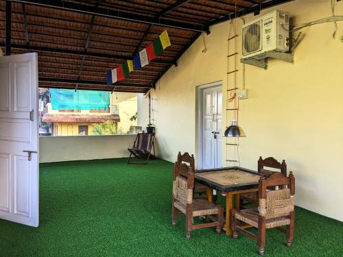 a room with a table and chairs on a green floor at Sakhey Homestay in Ratnagiri
