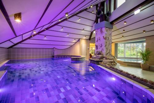 a swimming pool with purple lighting in a building at Köhlers Forsthaus Wellness & Genuss Hotel in Aurich