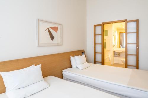 two beds in a room with a mirror at Novotel Vilnius Centre in Vilnius