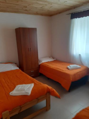 a room with two beds and a cabinet in it at Alojamiento Río Fenix Chico in Perito Moreno