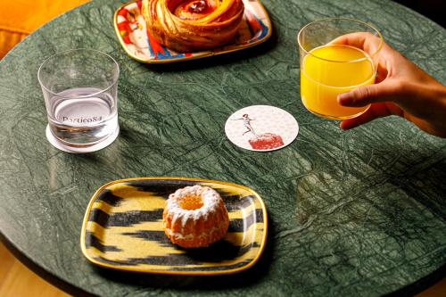a person holding a glass of orange juice and a plate of food at Urban Hive Milano in Milan