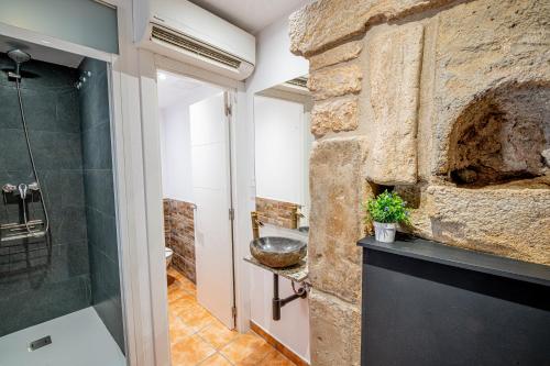 a bathroom with a stone wall and a shower at Planta baja en la muralla romana junto a la Catedral in Tarragona