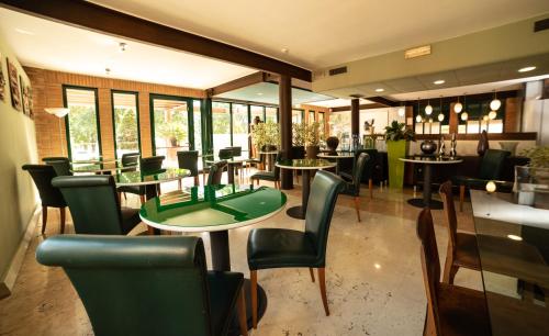 a restaurant with tables and chairs and a green table at HOTEL QUERINI Budget & Business Hotel Sandrigo in Sandrigo