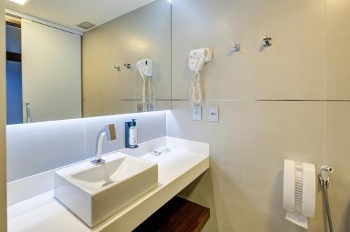 a white bathroom with a sink and a phone on the wall at FAST SLEEP Guarulhos by Slaviero Hotéis in Guarulhos