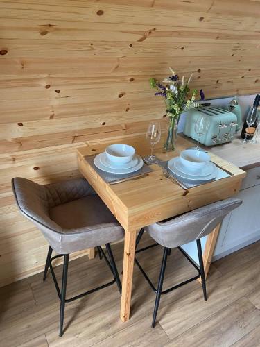 a wooden table with two chairs and a vase of flowers at Meall Ard Self Catering Pod - Isle of South Uist in Pollachar