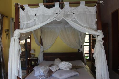 um quarto com uma cama de dossel e cortinas brancas em LA LIANE DE JADE 974-Lodge Le Palissandre - jacuzzi privatif - piscine em Le Bois de Nèfles