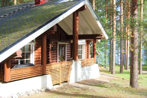 eine Blockhütte im Wald mit einer Veranda in der Unterkunft Holiday Home Honkakoli 1 in Kolinkylä
