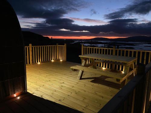 a wooden deck with a picnic table and lights at Meall Ard Self Catering Pod - Isle of South Uist in Pollachar