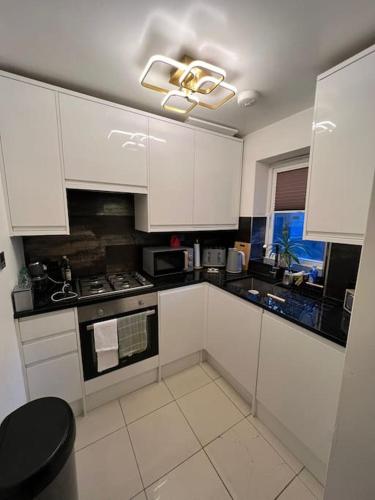a kitchen with white cabinets and a stove at GoldFlamingo in Mitcham