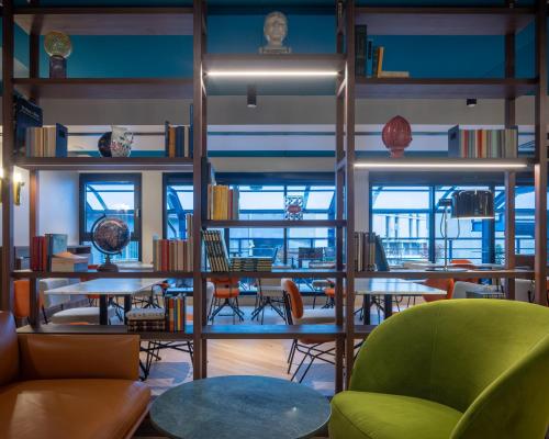 a library with tables and chairs and bookshelves at Urban Hive Milano in Milan