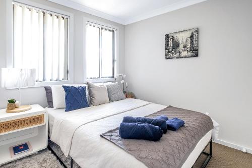 a bedroom with a large bed with blue pillows on it at Stylish 4BR Villa with Office l Modern and Comfy in Marsden Park