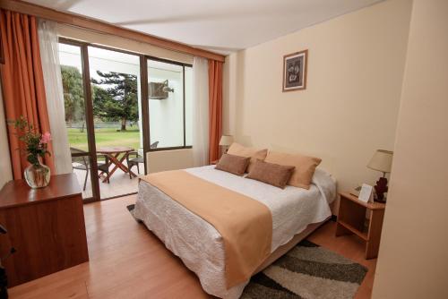 a bedroom with a bed and a balcony with a table at Hotel del Valle Azapa in Arica