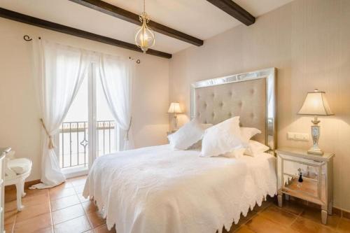 a bedroom with a large white bed and a window at Stylish 4 Bedroom Casa with Sea Views, Air Con & Communal Swimming Pool in La Herradura