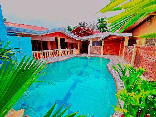 a villa with a swimming pool in front of a house at La-Familia Guest House in Siquijor