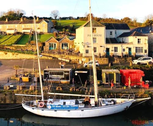 a boat docked in the water in front of a house at Stunning Yacht Sea Lion in Charlestown Harbour, Cornwall in Charlestown