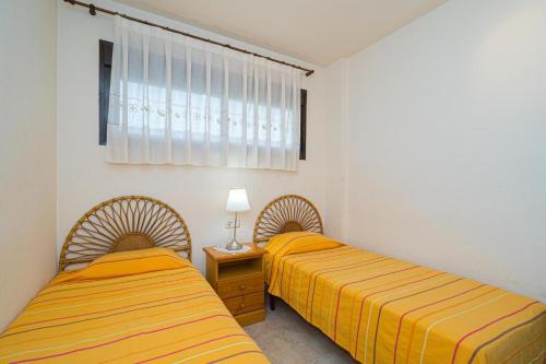 twee bedden in een kamer met gele lakens bij Estrella 1 Spaniahome in Albir